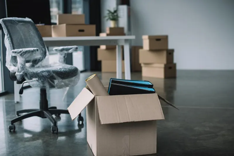 Bureaux en cours d'évacuation avec chaise emballée et cartons d'archives
